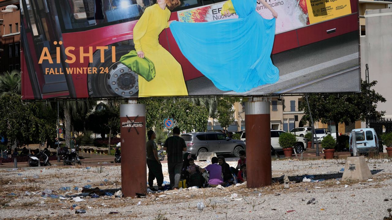 People who fled the southern suburb of Beirut amid ongoing Israeli airstrikes take a shade under a billboard advertising in downtown Beirut, Lebanon, on Saturday.