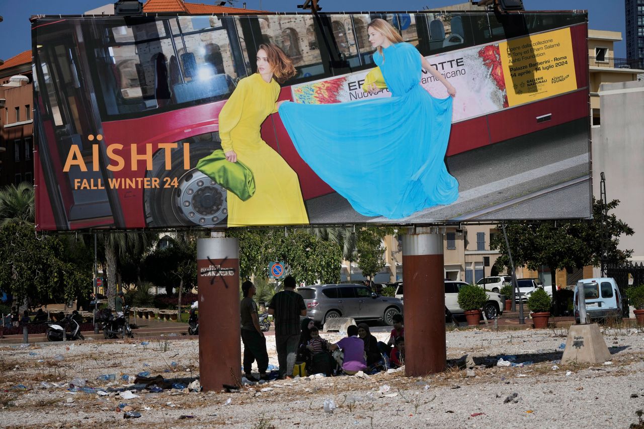 People who fled the southern suburb of Beirut amid ongoing Israeli airstrikes take a shade under a billboard advertising in downtown Beirut, Lebanon, on Saturday.