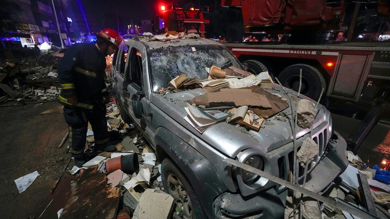 A firefighter inspects a damaged car near a building that was hit in an airstrike in Beirut, Lebanon early on Monday.