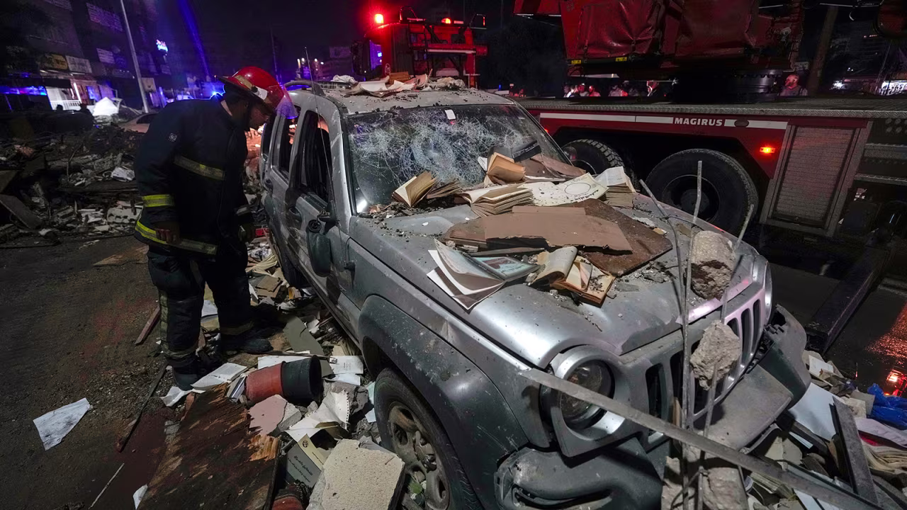 A firefighter inspects a damaged car near a building that was hit in an airstrike in Beirut, Lebanon early on Monday.