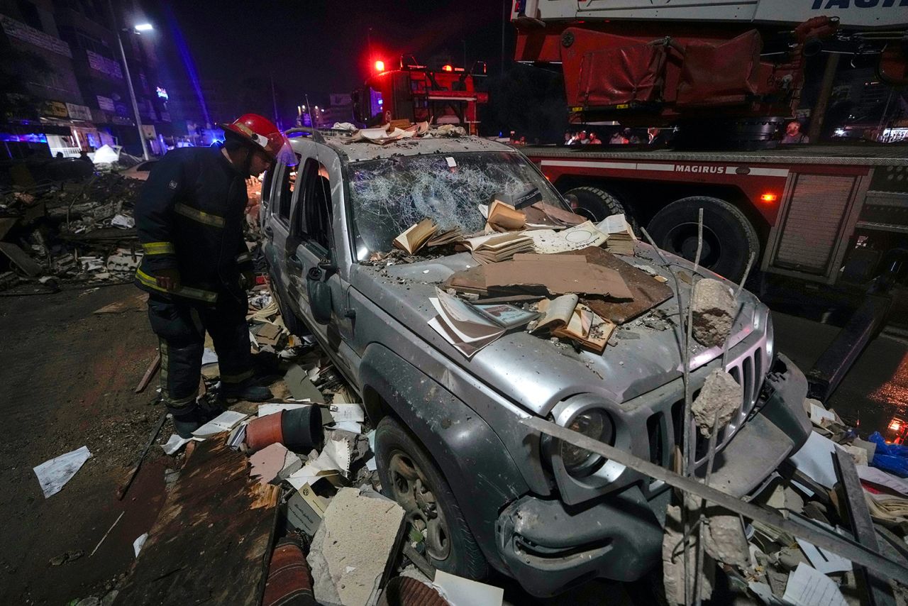 A firefighter inspects a damaged car near a building that was hit in an airstrike in Beirut, Lebanon early on Monday.