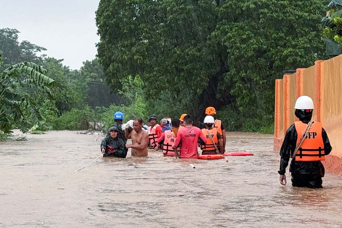 Rescuers help residents as they negotiate floods caused by powerful Typhoon Krathon locally called "Typhoon Julian" at Bacarra, Ilocos Norte province, northern Philippines on Monday, September 30, 2024.