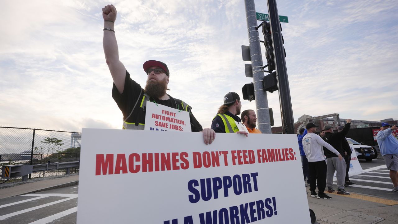 Longshoreman Franky Searle, of Boston, front, displays a placard in front an entrance to a container terminal near Boston Harbor on Tuesday.