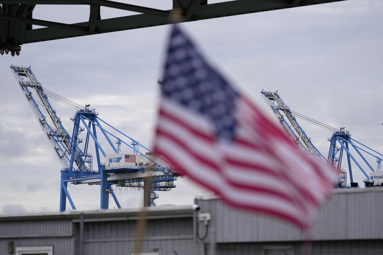 Striking longshoreman picket with a flag outside the Packer Avenue Marine Terminal Port on Tuesday in Philadelphia.