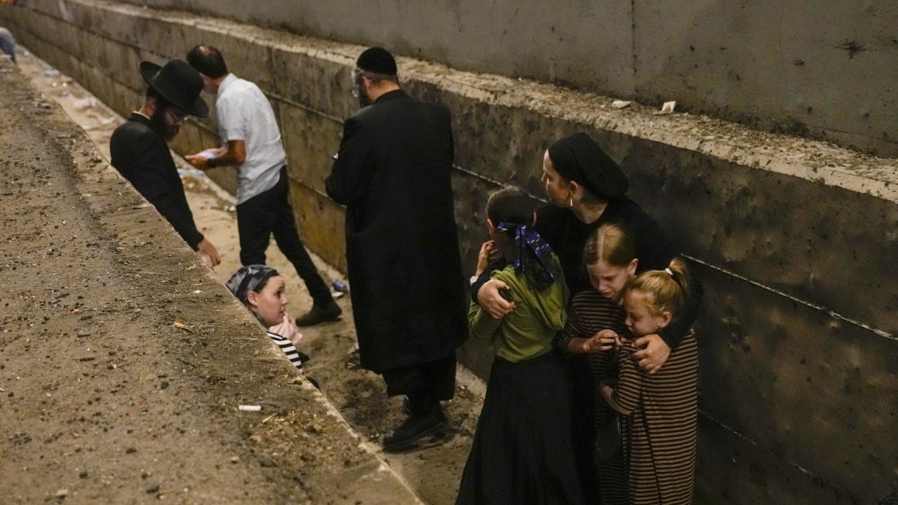 People take cover on the side of the road on a highway in Shoresh, Israel, on Tuesday.