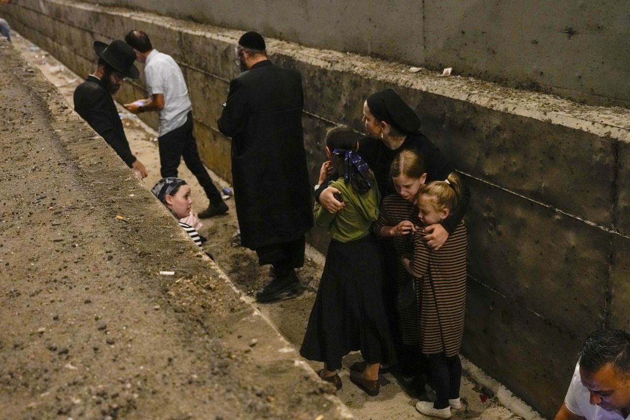 People take cover on the side of the road on a highway in Shoresh, Israel, on Tuesday.