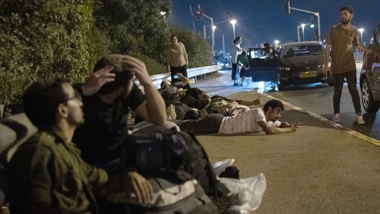 Israelis take cover as projectiles launched from Iran are being intercepted in the skies over in Rosh HaAyin, Israel, on October 1.