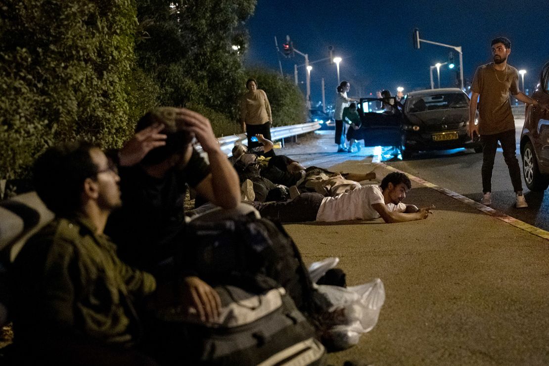 Israelis take cover as projectiles launched from Iran are intercepted in the skies over Rosh Haayin.