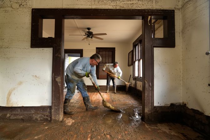 Ben Phillips, left, and his wife, Becca Phillips, scrape mud out of the living room of their home following flooding from Hurricane Helene in Marshall, North Carolina, on Tuesday, October 1.