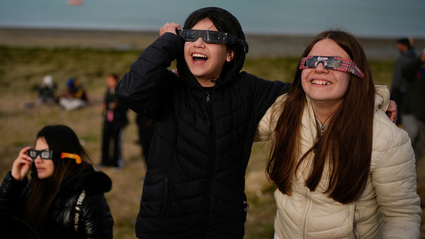 People watch as an annular solar eclipse appears Wednesday in the sky over Puerto San Julián, Argentina.