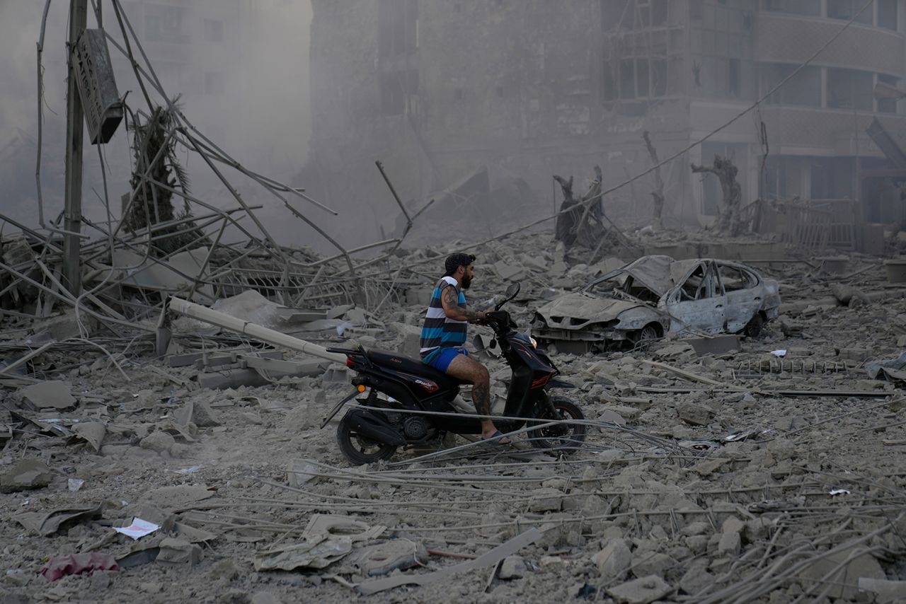 A man rides a scooter through the debris of destroyed buildings in Dahiyeh on Sunday.