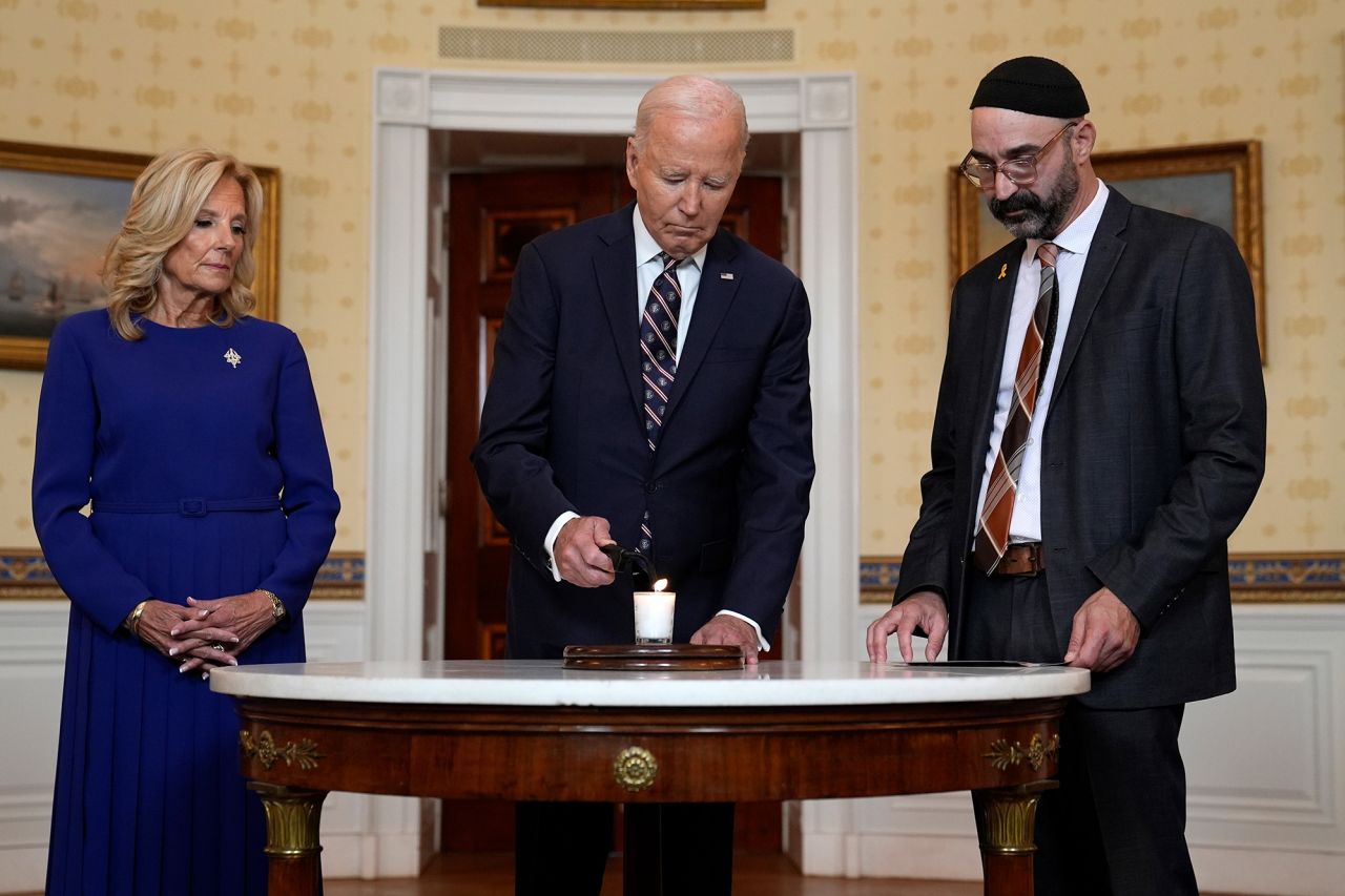 President Joe Biden, center, with first lady Jill Biden and Rabbi Aaron Alexander, lights a memorial candle in the Blue Room of the White House on Monday.