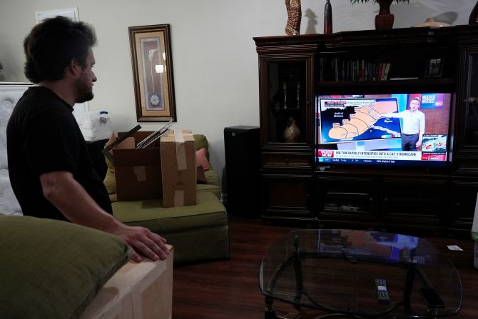 Domenic Gerald takes a break to watch the latest forecast while packing up his father's vacation home in Fort Myers Beach on Monday.