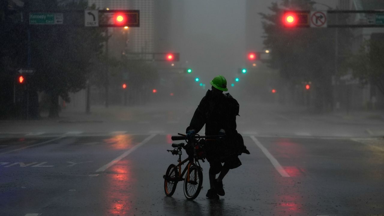 Ron Rook, who said he was looking for people in need of help or debris to clear, walks through windy and rainy conditions in downtown Tampa, Florida, on Wednesday.