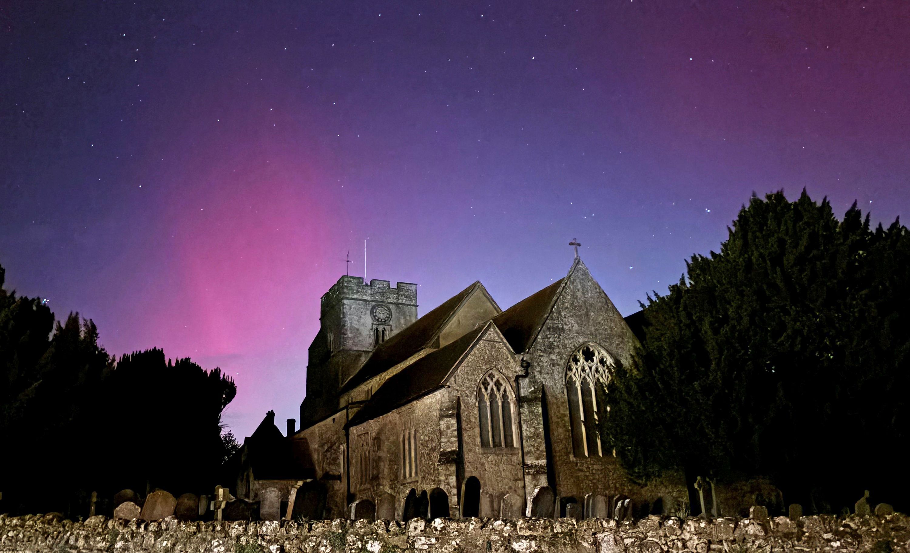 Auroras light the sky over Great Chart Church in Ashford, England, on Thursday.