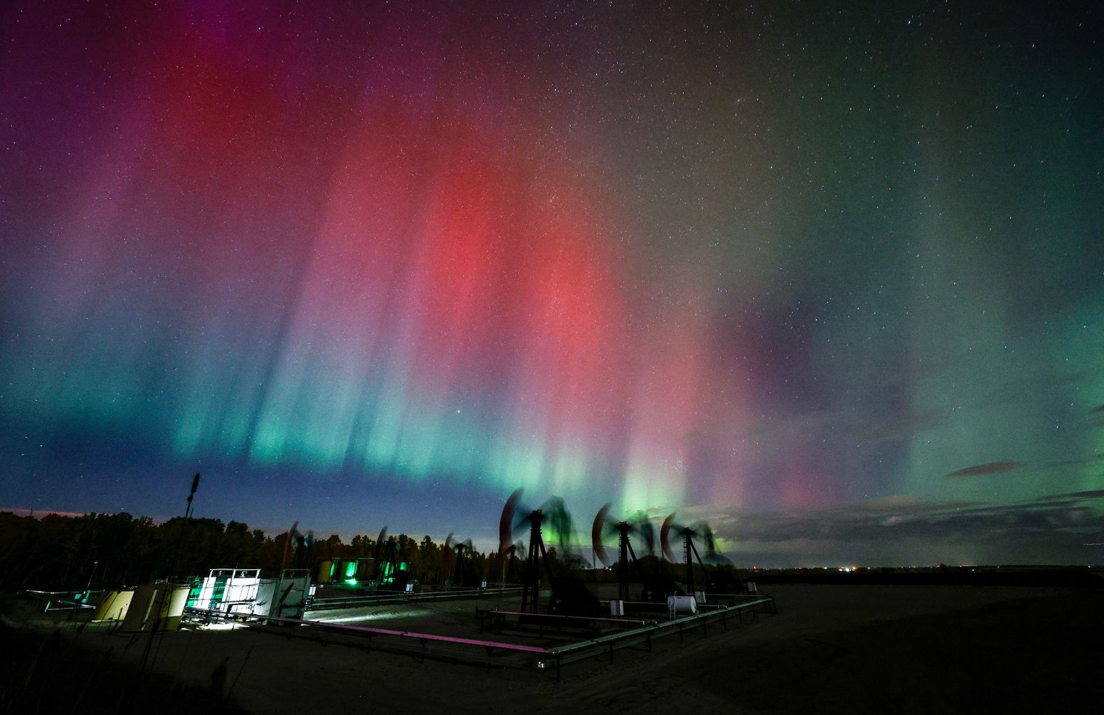 The northern lights are seen over pumpjacks as they draw out oil and gas from well heads near Cremona, Alberta, Canada on Thursday.