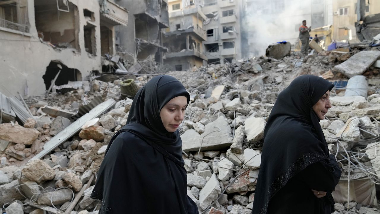 Lebanese women pass destroyed buildings hit by an Israeli airstrike, in Beirut, Lebanon, on October 11.