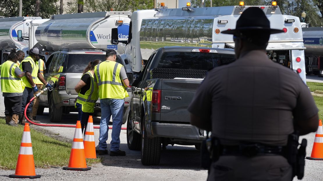 A Florida Highway Patrol officer watches fuel depot workers distribute gasoline to residents Saturday, Oct. 12, 2024, in Plant City, Fla. Gas stations are slow to reopen following the impacts of Hurricane Milton.