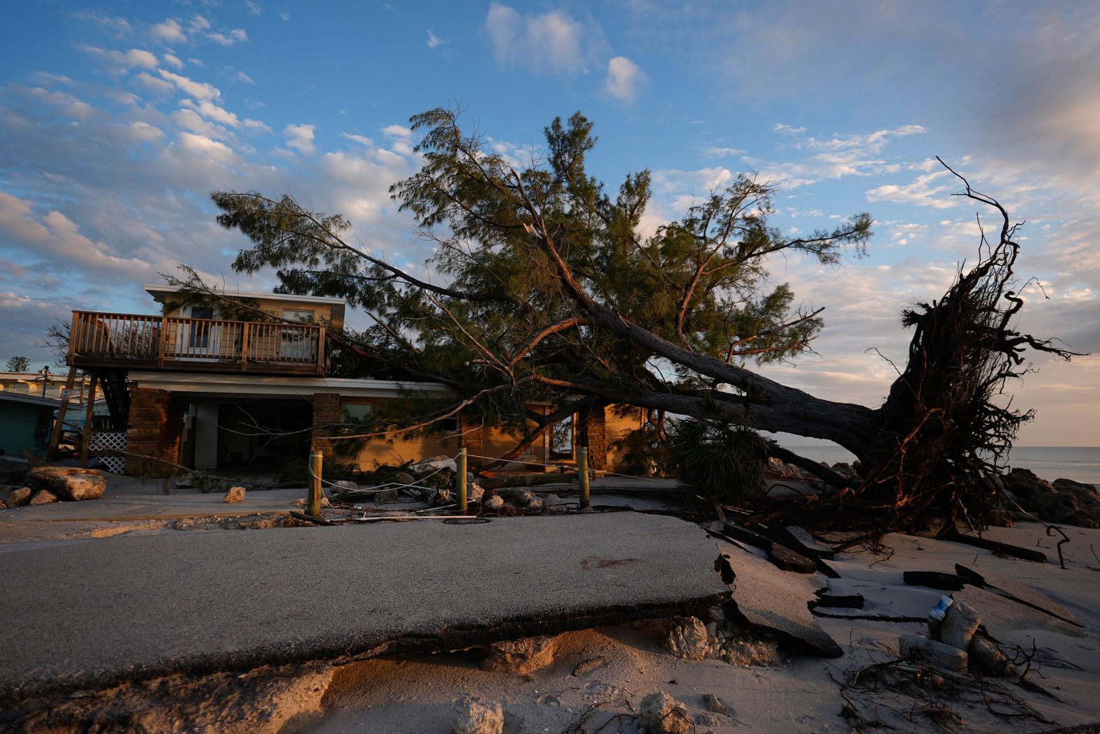 A toppled tree lies on a home on Manasota Key on Saturday.