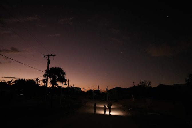 A family walks back up a sand-coated street on Saturday, October 12, after checking on their storm-damaged home on Manasota Key.