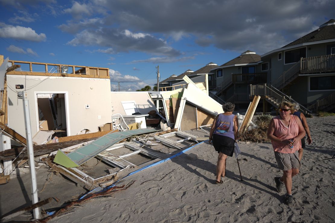 Neighbors look at what remains of a home torn apart by Hurricane Milton storm surge, in a 55+ mobile home community on Manasota Key, in Englewood, Florida, Sunday, October 13, 2024.