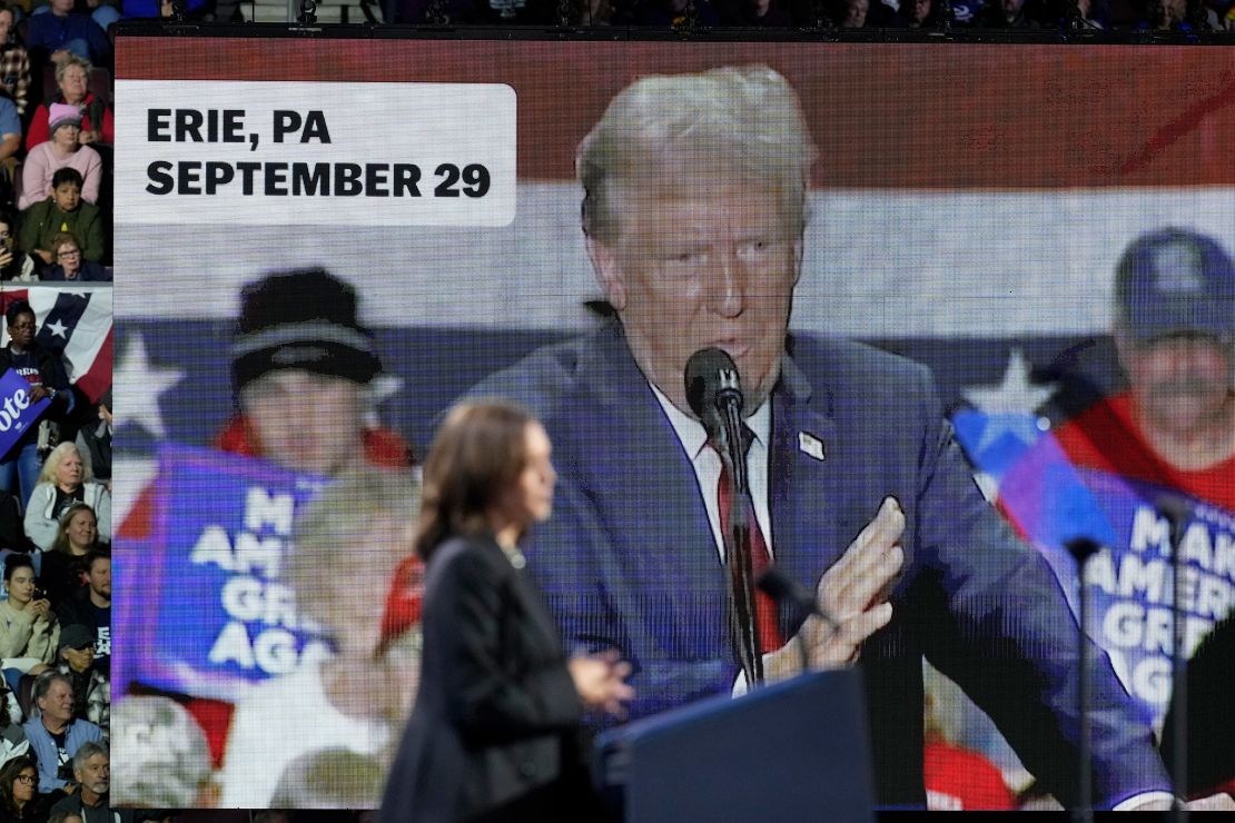 An image of former President Donald Trump appears on the screen as Vice President Kamala Harris speaks during a campaign rally in Erie, Pennsylvania, on October 14, 2024.