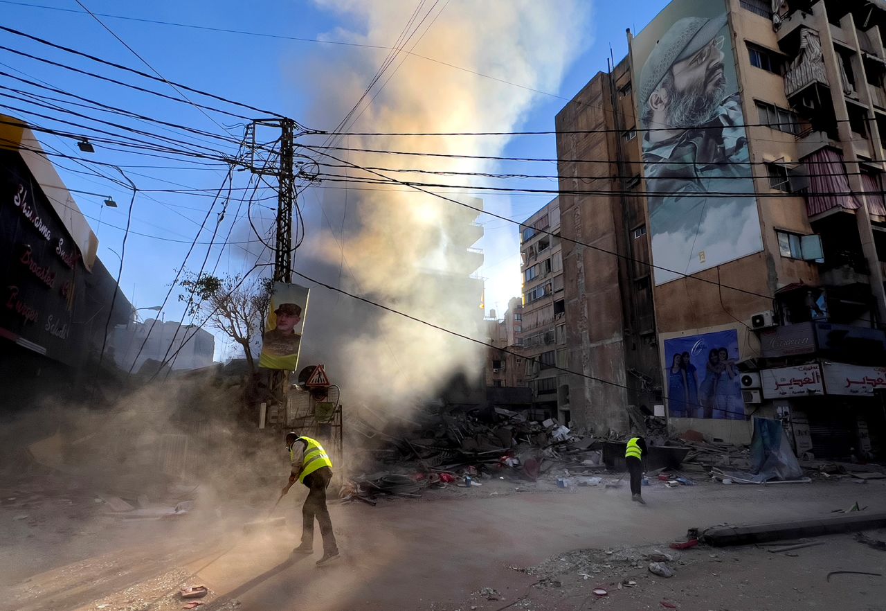 Workers clean a street as smoke rises from a destroyed building that was hit by an Israeli airstrike in Dahiyeh, in the southern suburb of Beirut, Lebanon on October 20.