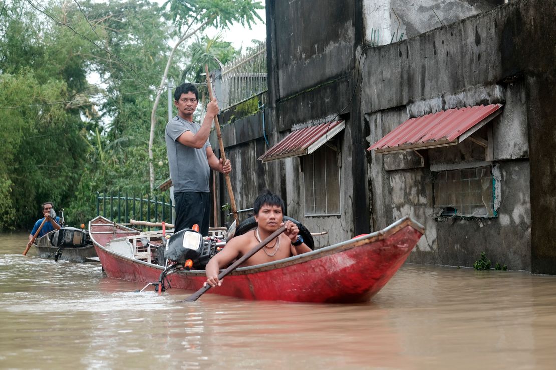 Residents use a boat to recover items from their flooded homes as the storm inundated Libon town, Albay province, Philippines on Thursday October 24, 2024.