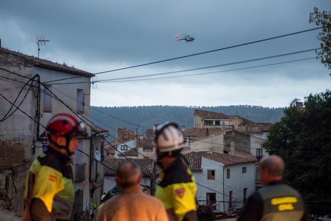 Rescue workers look at a helicopter flying overhead in Letur on Tuesday.