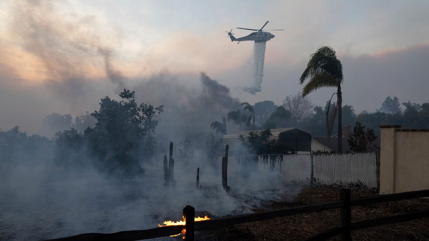 A helicopter drops water over a burning structure during a fast-moving wildfire in Moorpark, California.