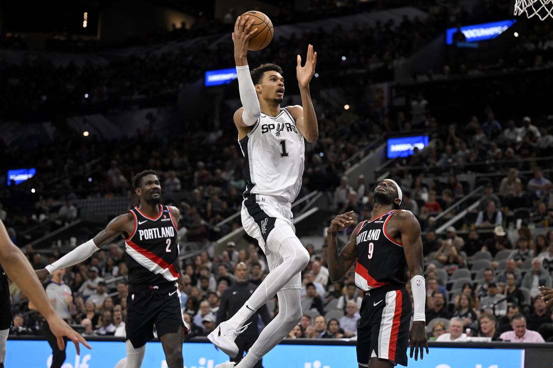 San Antonio Spurs' Victor Wembanyama goes to the basket against Portland Trail Blazers' Jerami Grant and Deandre Ayton.