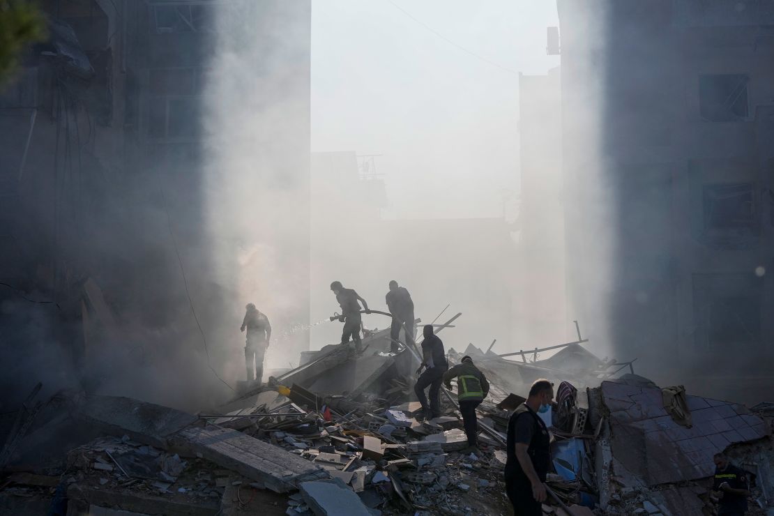 Civil defense workers extinguish a fire as smoke rises from the site of the airstrike.