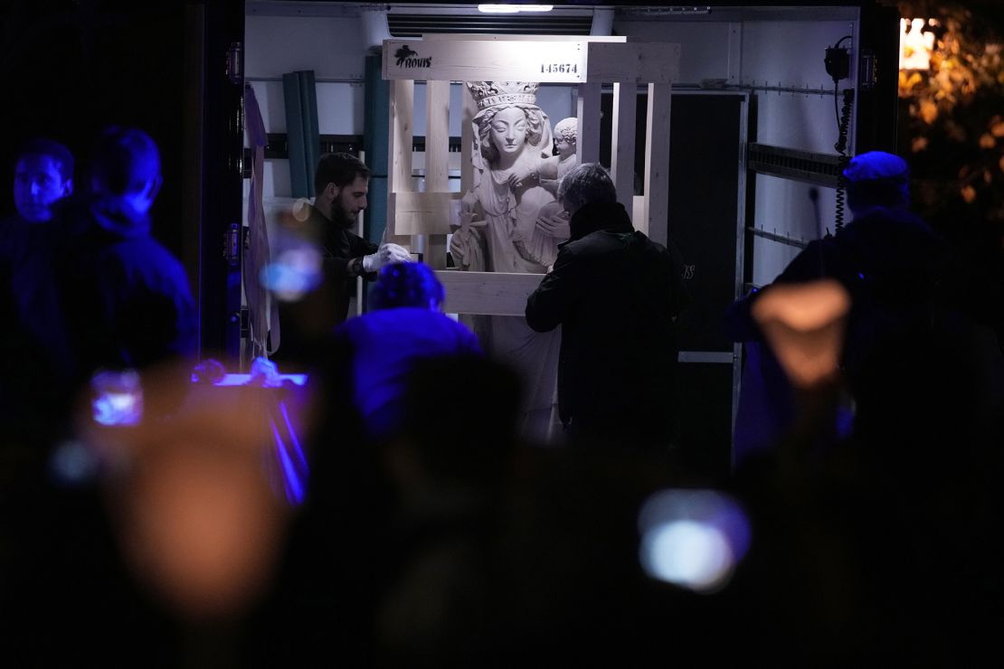 Workers protect the Virgin Mary statue, which has become a symbol of resilence as it did not suffer from the 2019 fire, before its return in the Notre Dame on November 15.