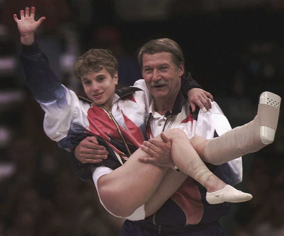 USA's Kerri Strug is carried by her coach, Bela Karolyi, as she waves to the crowd on her way to receiving her gold medal for the women's team gymnastics competition, at the Centennial Summer Olympic Games in Atlanta, July 23, 1996.