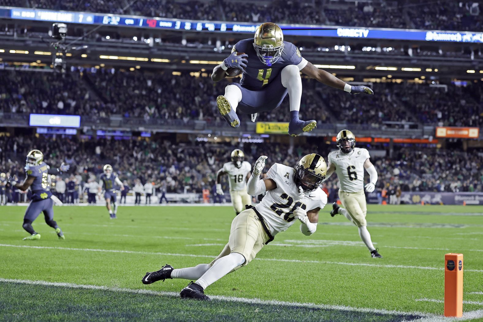 Notre Dame running back Jeremiyah Love (4) leaps over Army cornerback Donavon Platt to score a touchdown during the first half of an NCAA college football game at Yankee Stadium, Saturday, Nov. 23, 2024, in New York. (AP Photo/Adam Hunger)