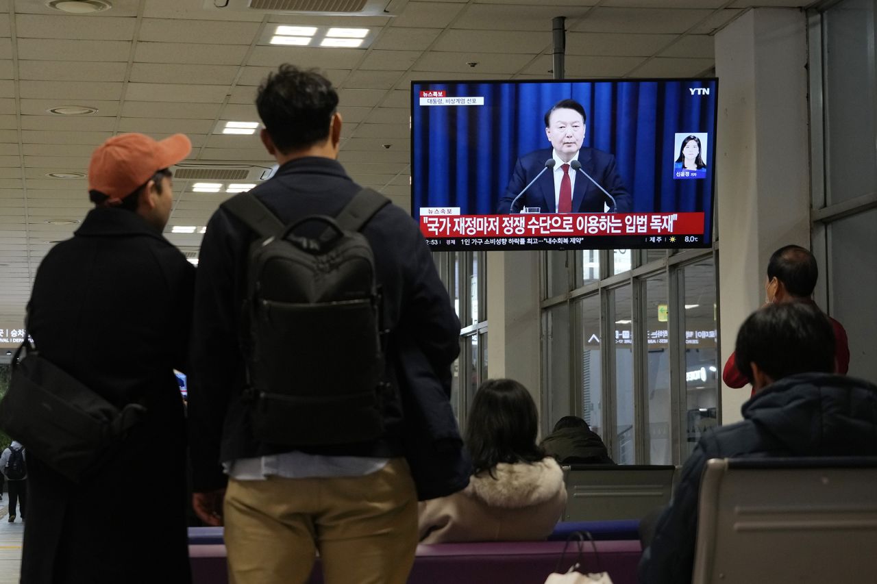 People watch a TV screen showing South Korean President Yoon Suk Yeol's televised briefing at a bus terminal in Seoul, South Korea, on December 3.