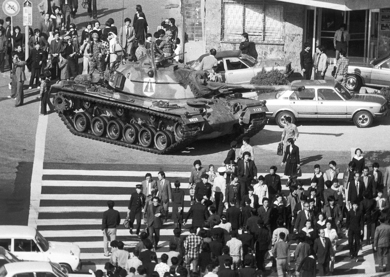 Seoul citizens walk beside an army tank on October 27, 1979, after martial law was declared following the death of President Park Chung-Hee.