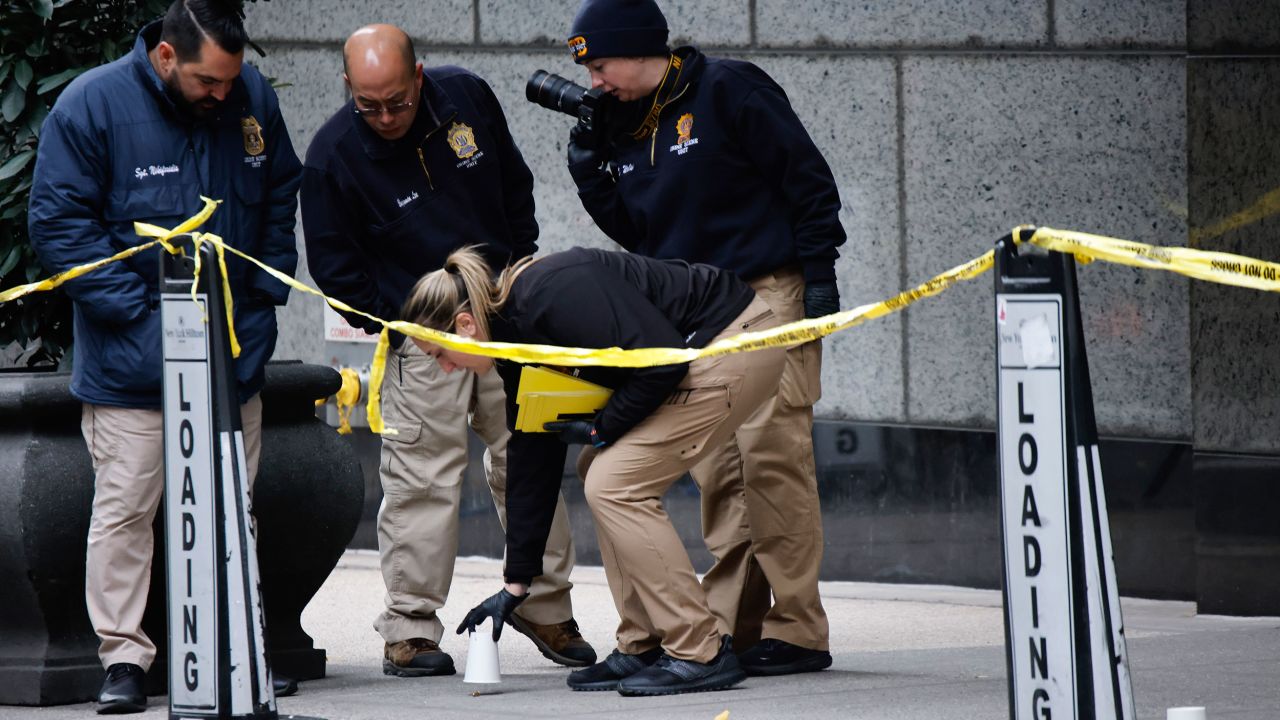 Members of the New York police crime scene unit pick up cups marking the spots where bullets lie as they investigate the scene outside the Hilton Hotel in midtown Manhattan where Brian Thompson, the CEO of UnitedHealthcare, was fatally shot Wednesday, Wednesday, Dec. 4, 2024, in New York. (AP Photo/Stefan Jeremiah)