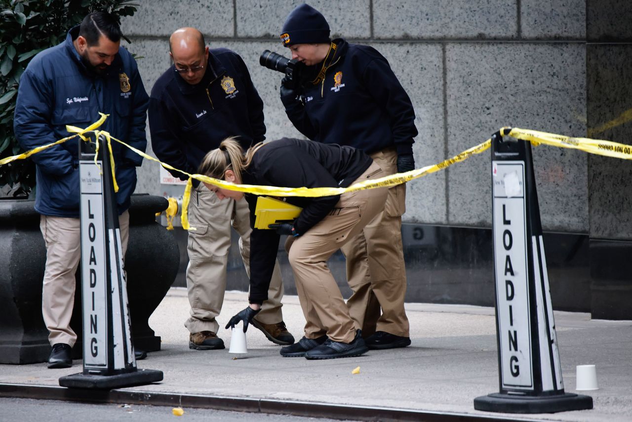 Members of the New York police crime scene unit pick up cups marking the spots where bullets lie as they investigate the scene outside the Hilton hotel in midtown Manhattan on Wednesday in New York.