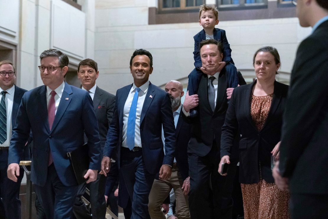 Vivek Ramaswamy, fourth from left, and Elon Musk, who is carrying his son X Æ A-Xii, arrive for a roundtable meeting to discuss President-elect Donald Trump's planned Department of Government Efficiency, on Capitol Hill in Washington, DC, on December 5.