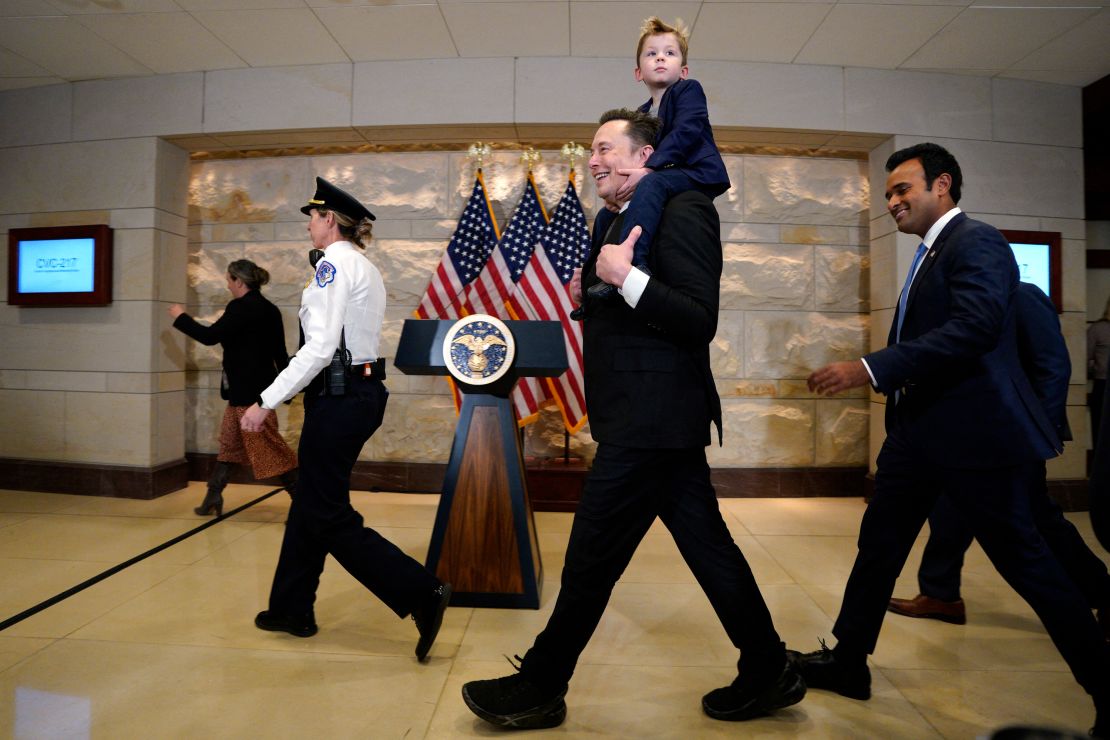 Elon Musk, com seu filho nos ombros, e Vivek Ramaswamy caminham no Capitólio, em Washington DC, em 5 de dezembro de 2024.