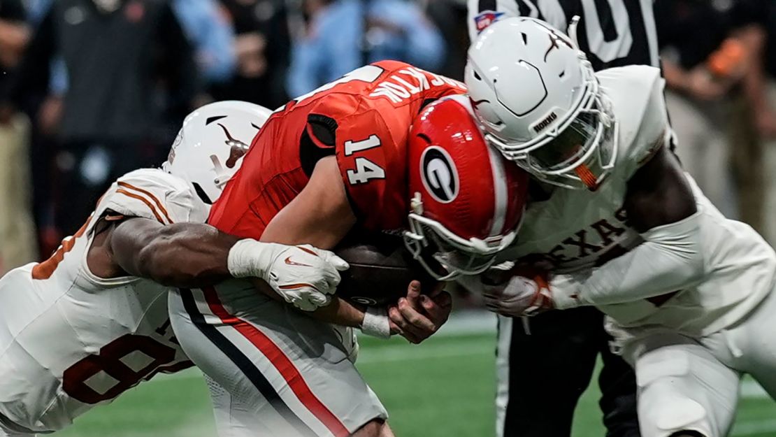 Georgia quarterback Gunner Stockton (14) and Texas defensive back Andrew Mukuba (4) collide in overtime of the SEC championship game.