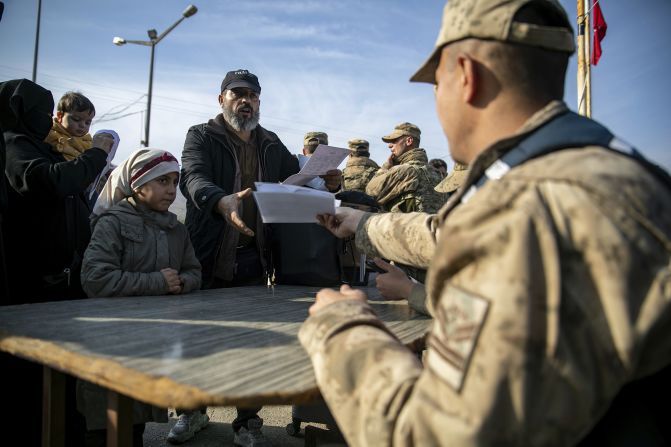 A Syrian man gives documents to a Turkish gendarme to be able to cross into Syria from Turkey at the Cilvegozu border gate near the town of Antakya, southern Turkey, on December 10.