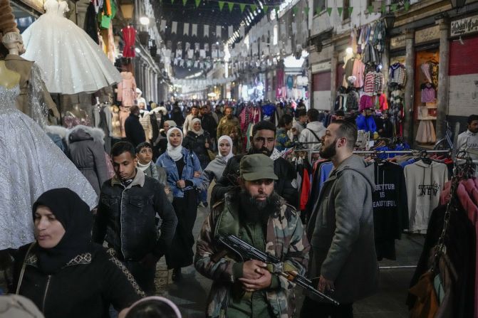 Armed fighters walk among the crowds at the Al-Hamidiyeh market inside the old walled city of Damascus on December 10.