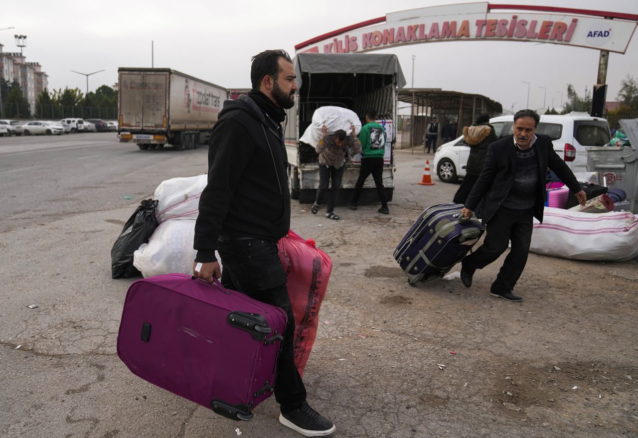 Syrians carry their belongings as they prepare to cross into Syria from Turkey.