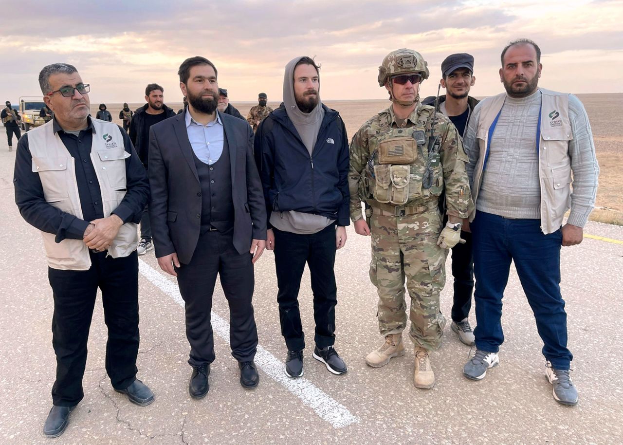 Travis Timmerman, center, stands with a member of the US military and representatives of Syria's transitional government and opposition activists near the Syria-Jordanian border, on December 13.