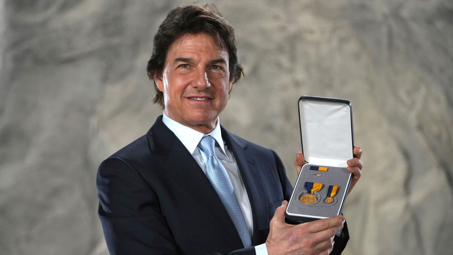 Tom Cruise posing with the Distinguished Public Service Award he received Tuesday from The United States Secretary of the Navy Carlos Del Toro in London.
