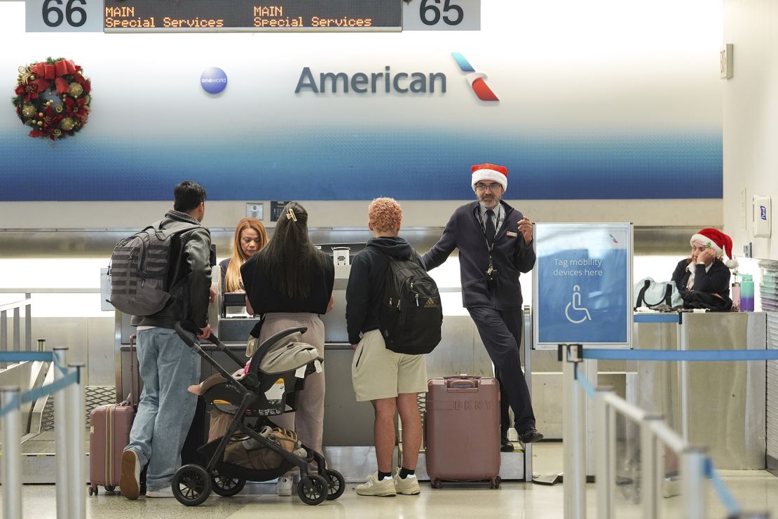 American Airlines employees, some wearing Santa Claus hats, check in travelers in the American terminal at Miami International Airport, on Christmas Eve, Tuesday, Dec. 24, 2024, in Miami.