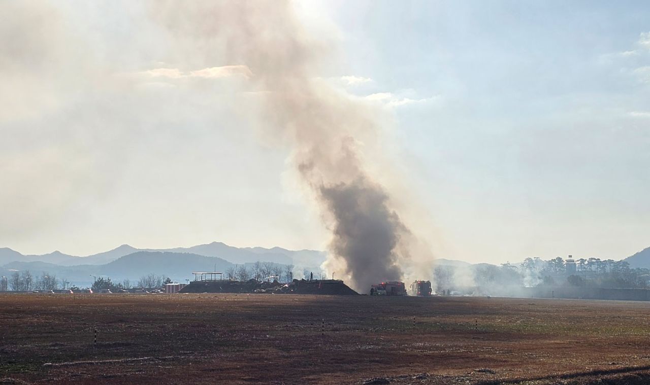 Firefighters work to extinguish a fire off the runway of Muan International Airport.