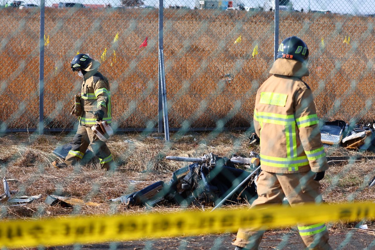 Firefighters search near the debris at the site of a plane fire at the Muan International Airport on December 29.